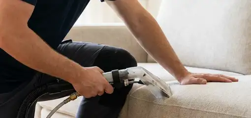 Professional upholstery cleaner deep-cleaning a fabric sofa with a handheld extraction tool, Minneapolis, MN.